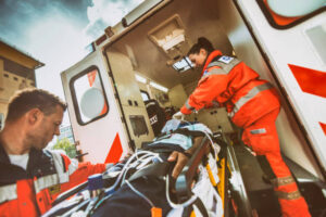 Paramedic assists patient on a stretcher in an ambulance.